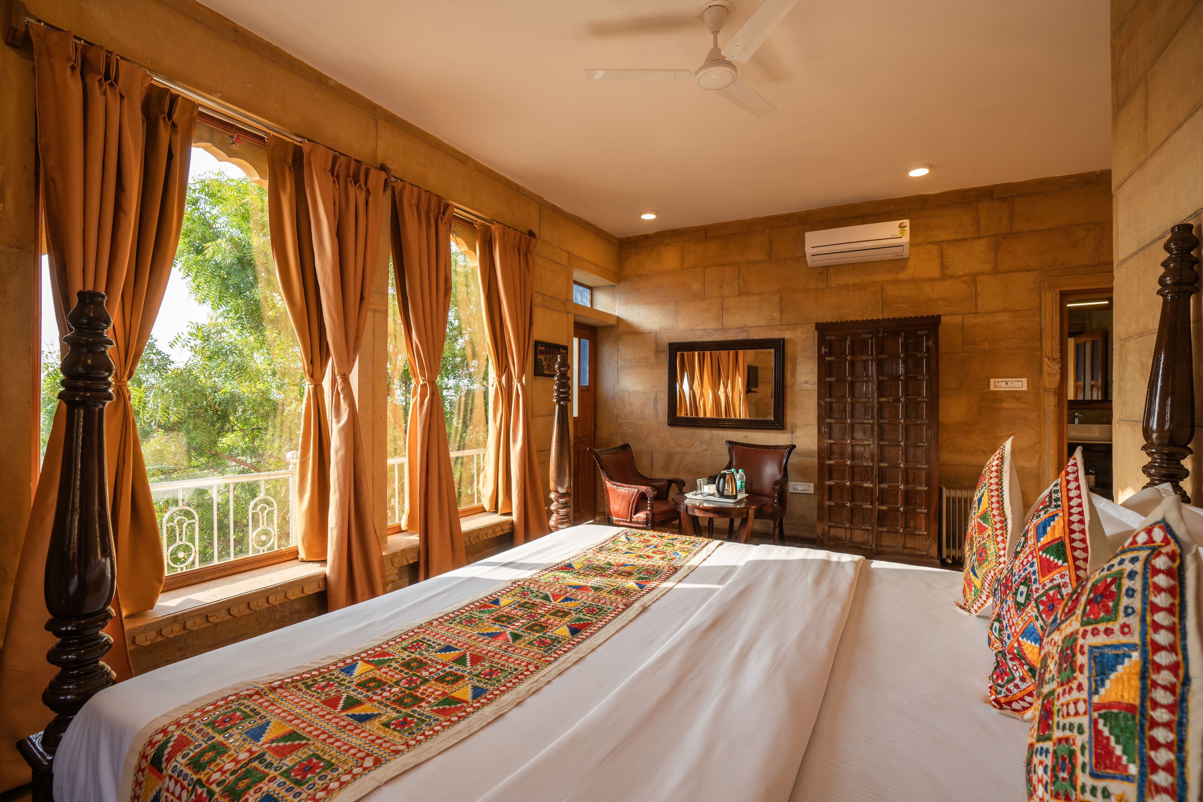 A spacious bedroom with a large bed, a ceiling fan, and a view of the outdoors through large windows.