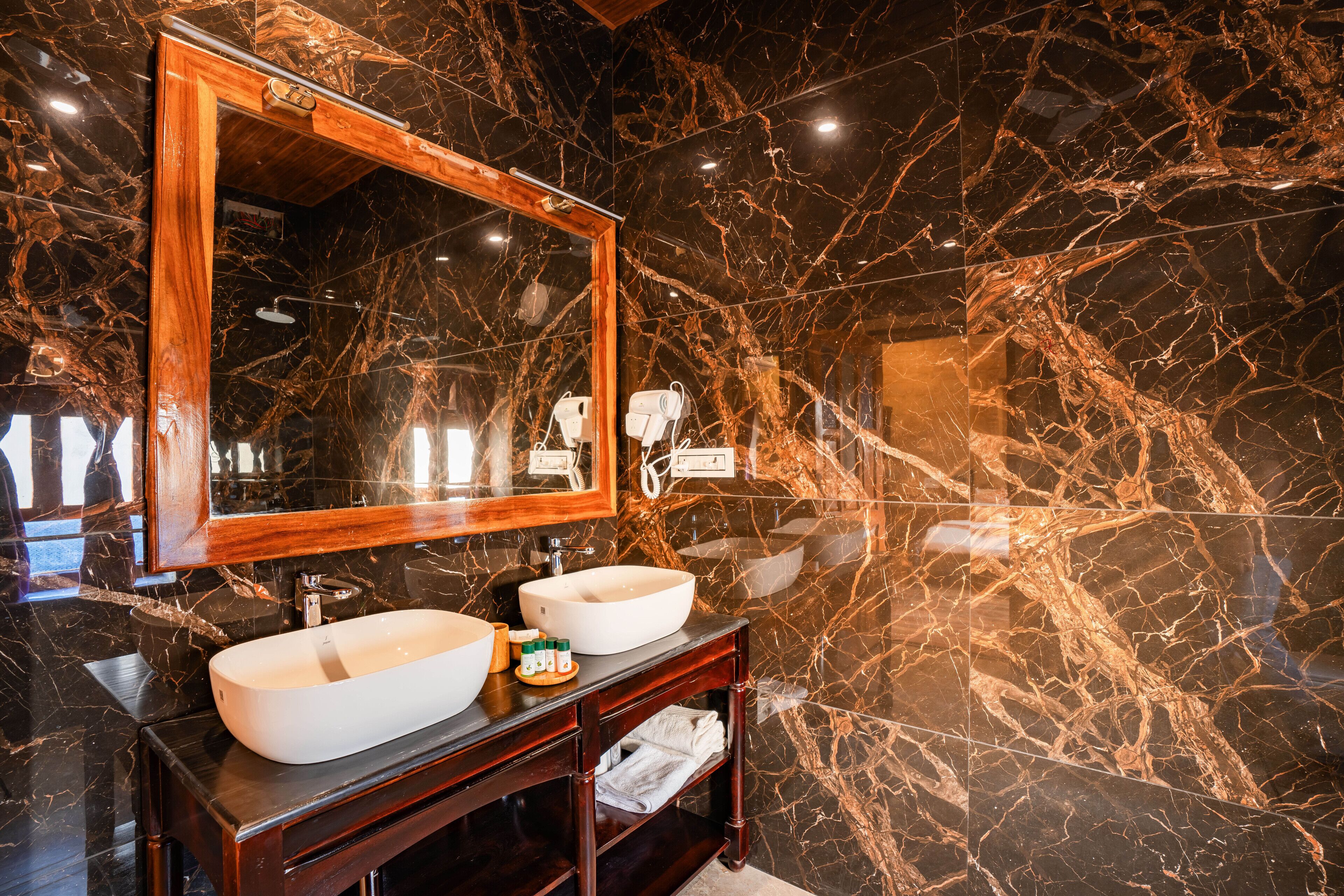 A bathroom with a large mirror, two sinks, and a marble backsplash.