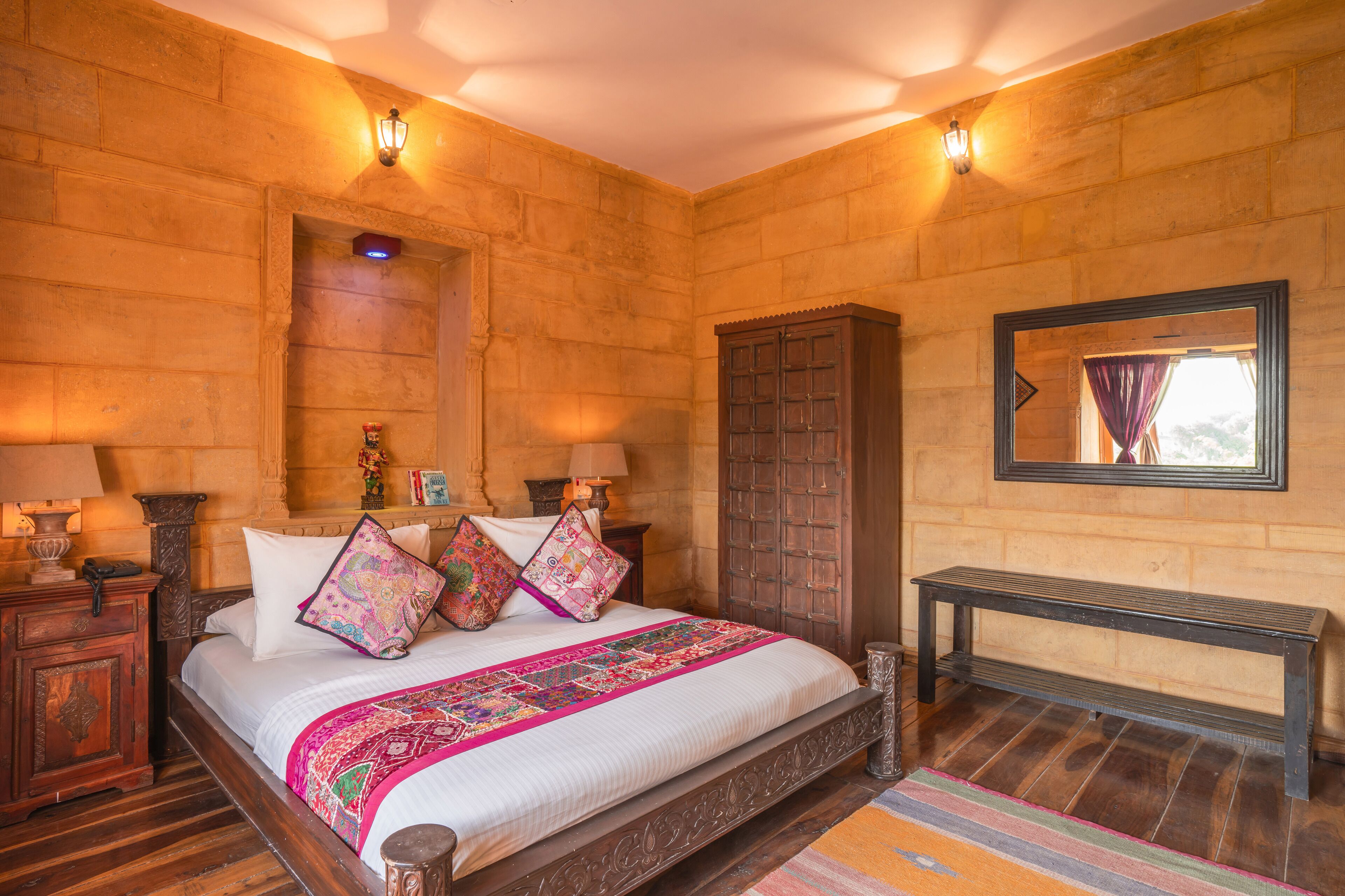 A bedroom with a large bed, wooden headboard, and a nightstand with a lamp.