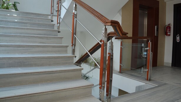 A staircase with wooden handrails and glass railings, leading to an upper floor. - Hotel Holy Himalaya (Kathmandu)