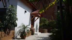 A courtyard with a white building, a brick wall, and various potted plants. - Hotel Holy Himalaya (Kathmandu)