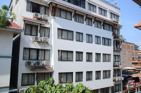 Un hotel de varios pisos con aire acondicionado, balcones y techo de tejas.