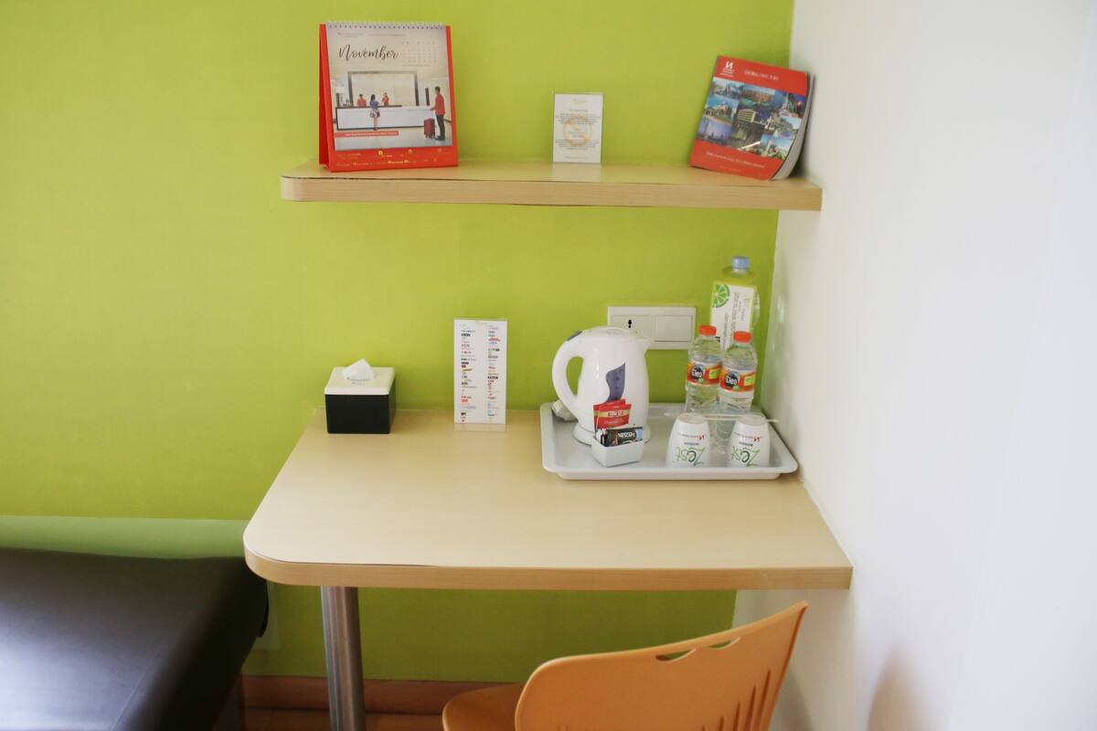 A small table with a tray containing a kettle, a tissue box, a menu, and a bottle of water.