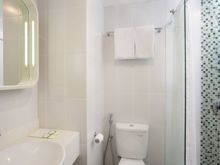 A bathroom with a sink, mirror, toilet, and shower.