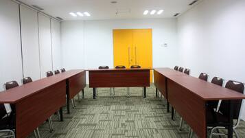 Un salón de conferencias con una larga mesa, sillas y una puerta amarilla.