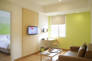Una habitación de hotel moderna con una cama, un escritorio con silla, un televisor y una ventana con persianas.