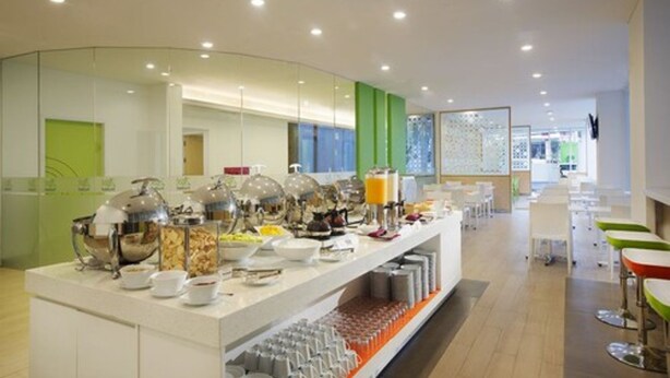 A modern breakfast buffet with various food items and a seating area with tables and chairs. - Zest Bogor by Swiss-Belhotel International (Bogor)