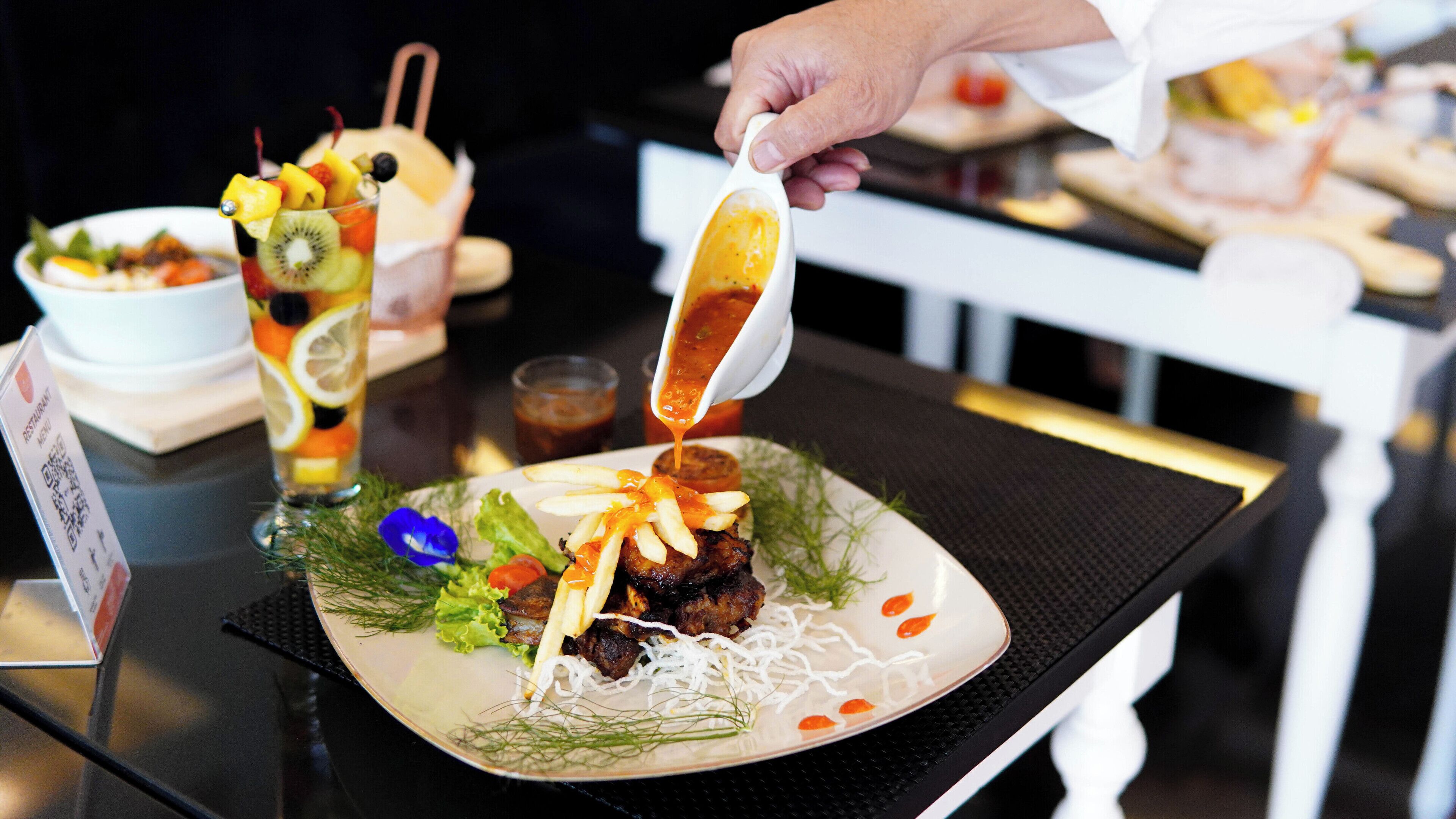 Une table à manger avec une assiette de nourriture, un verre et un panneau avec un code QR.