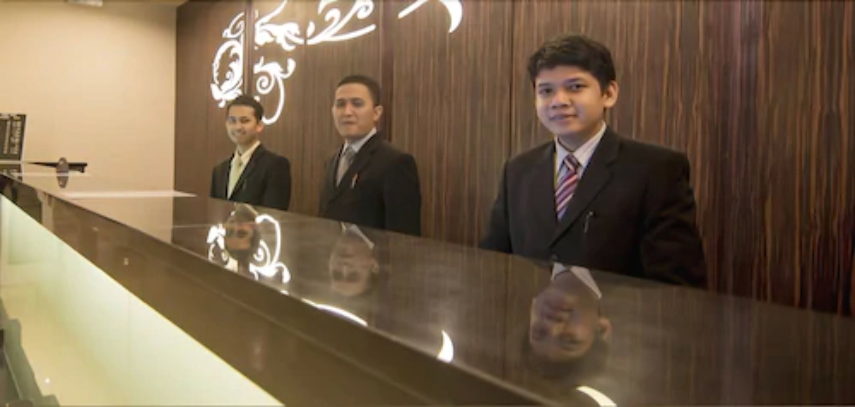 A reception desk with three individuals standing behind it.