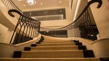 Una imponente escalera con candelabro, que conduce a un balcón con vistas.