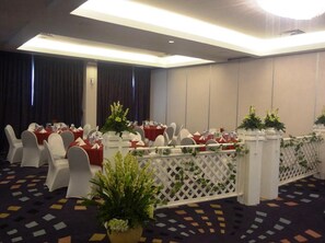 A conference room with round tables, white chairs, and red tablecloths. - Diradja Hotel (Jakarta)
