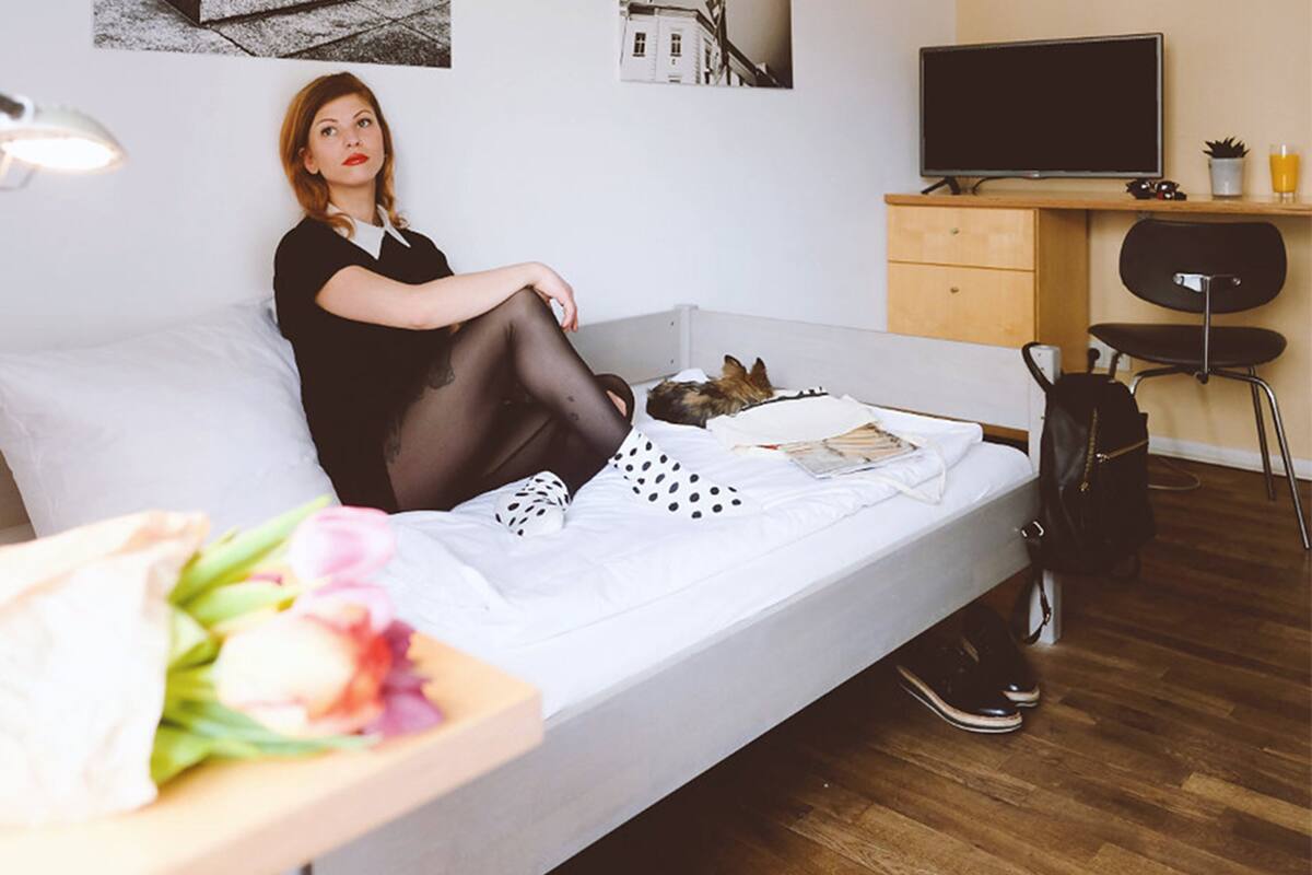 A modern room with a bed, a desk, a chair, and a small table with flowers.
