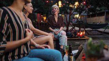 Eine Gruppe von Menschen sitzt abends draußen, mit einer Hängematte und einem Tisch mit einer Flasche und einer Kerze.