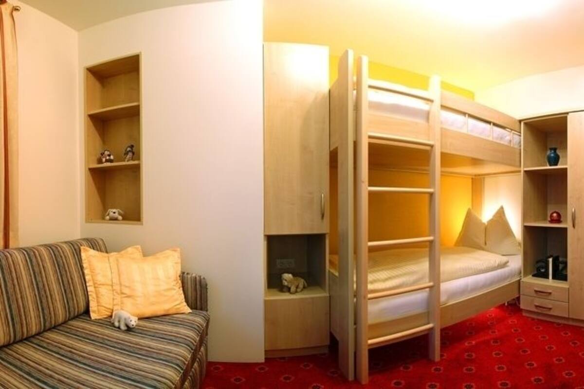 Ein kleines Zimmer mit Etagenbett, einer Schlafcouch und einem Kleiderschrank.