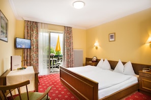 Habitación de hotel con una cama grande, un escritorio con una computadora, una silla y vistas al exterior a través de una puerta corrediza.