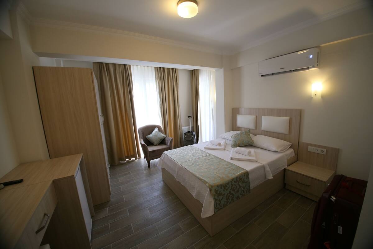Ein Hotelzimmer mit einem Bett, einem Schreibtisch, einem Stuhl, einer Klimaanlage und einem Kleiderschrank.