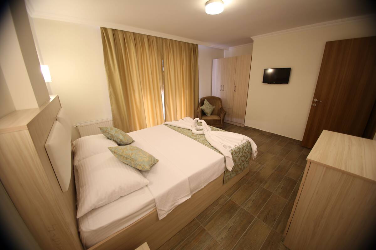 Ein Hotelzimmer mit Bett, Sessel, Fernseher und Kleiderschrank.