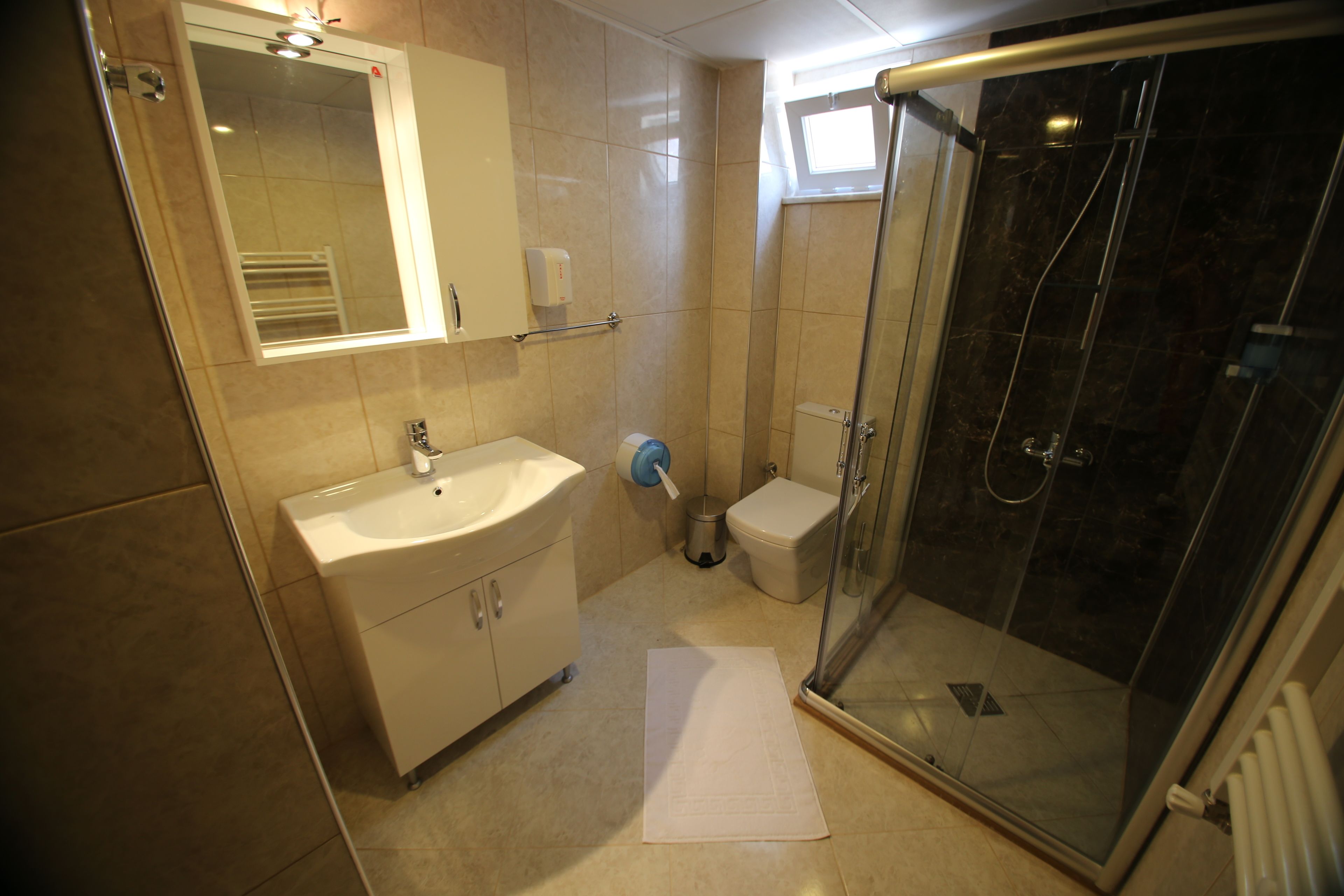 A bathroom with a sink, mirror, toilet, and glass-enclosed shower.