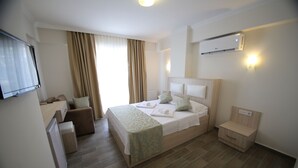 Ein Hotelzimmer mit Bett, Schreibtisch, Stuhl, Nachttisch und Klimaanlage.