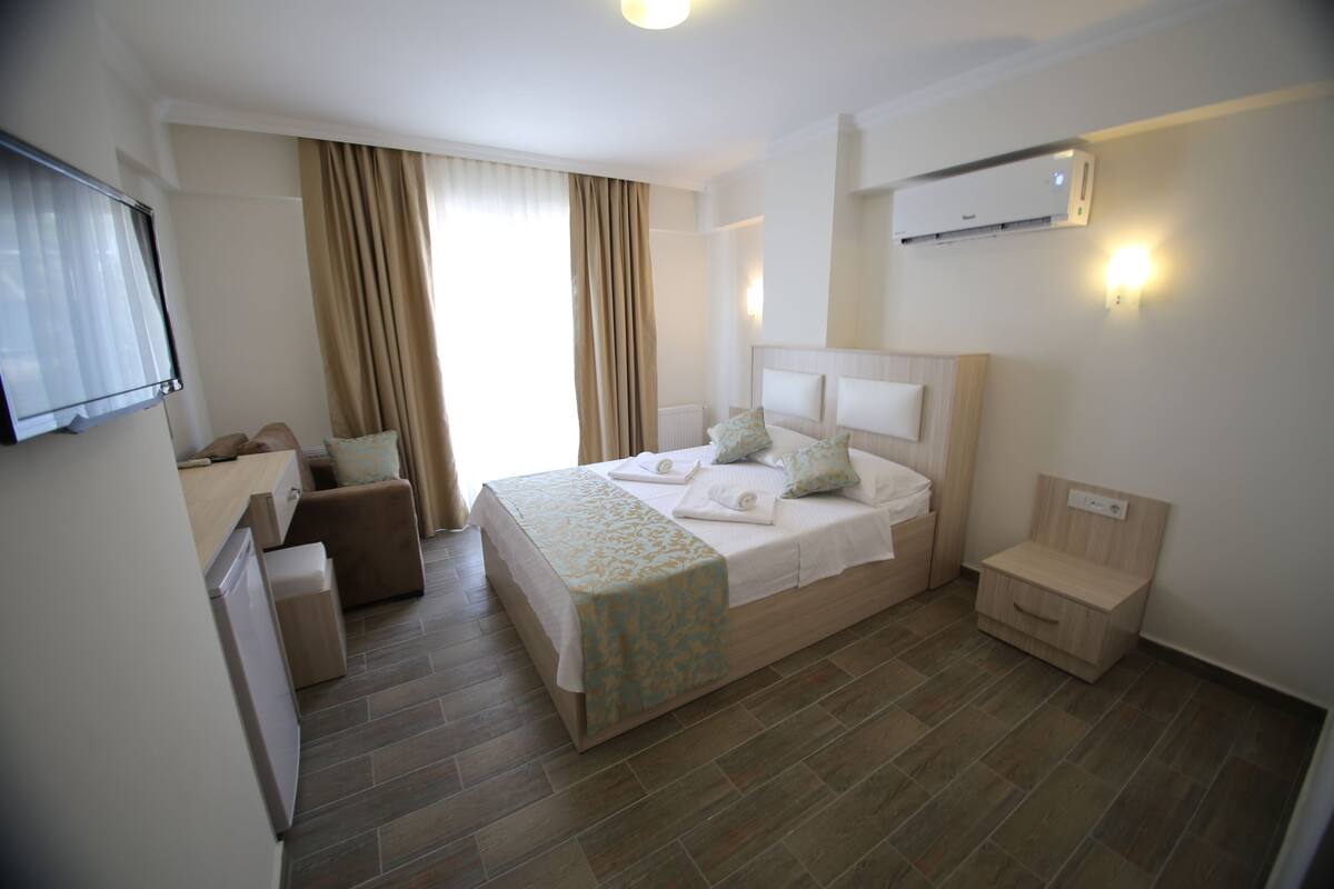 Ein Hotelzimmer mit Bett, Schreibtisch, Stuhl, Nachttisch und Klimaanlage.
