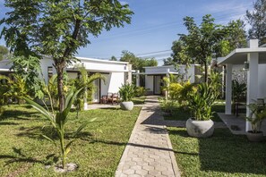 A courtyard with a paved walkway, surrounded by white buildings and lush greenery. - Sahaa Beach Resort (Sihanoukville)
