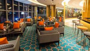 Un moderno vestíbulo de hotel con techo curvo, ventanas amplias y una alfombra geométrica de colores.