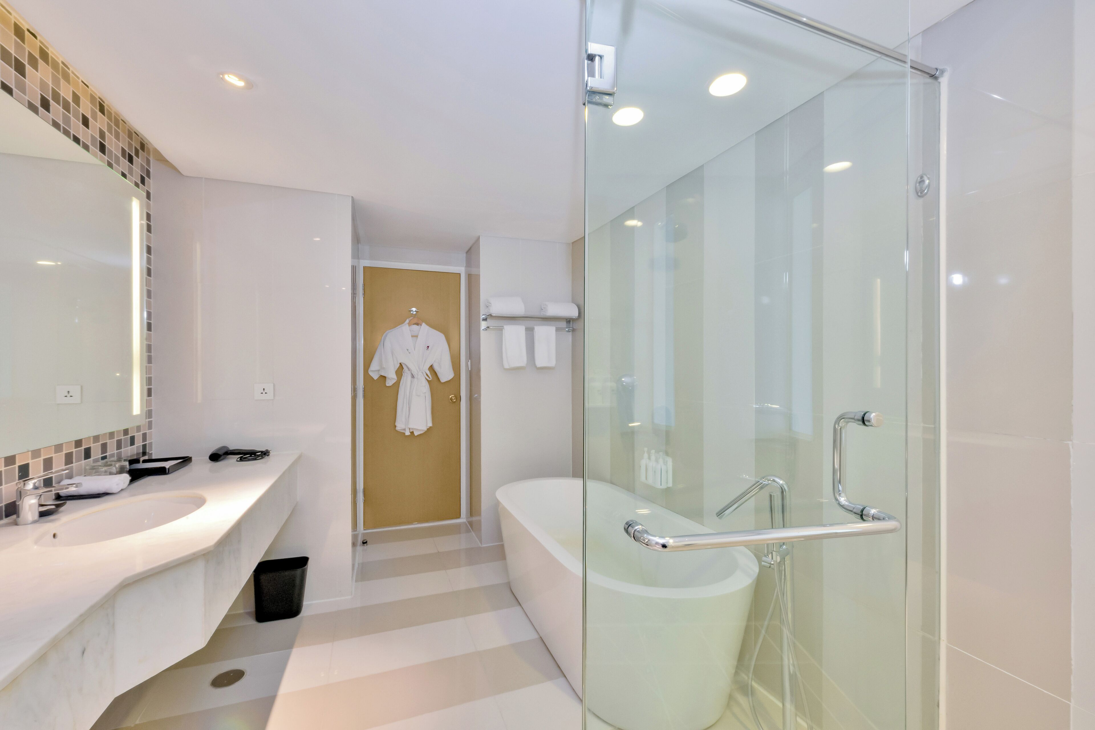 A modern bathroom with a glass-enclosed shower, a standalone bathtub, and a vanity with a mirror.