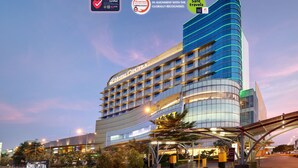 Un hotel moderno con una fachada curva, varios pisos y una entrada destacada con toldo.