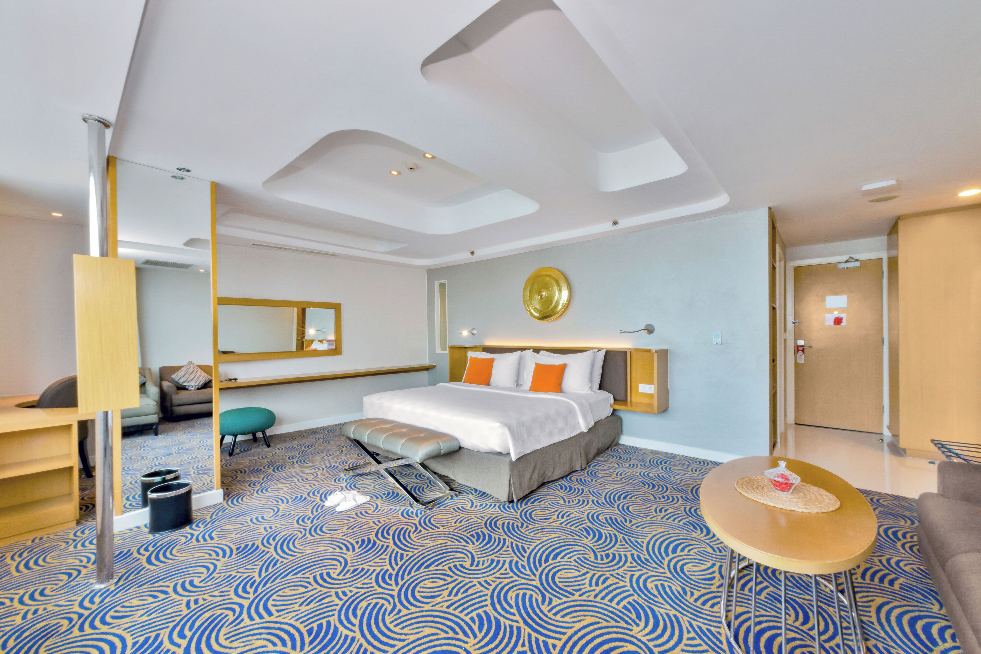 Een moderne hotelkamer met een groot bed, een bureau, een stoel, een ronde tafel en een spiegel.
