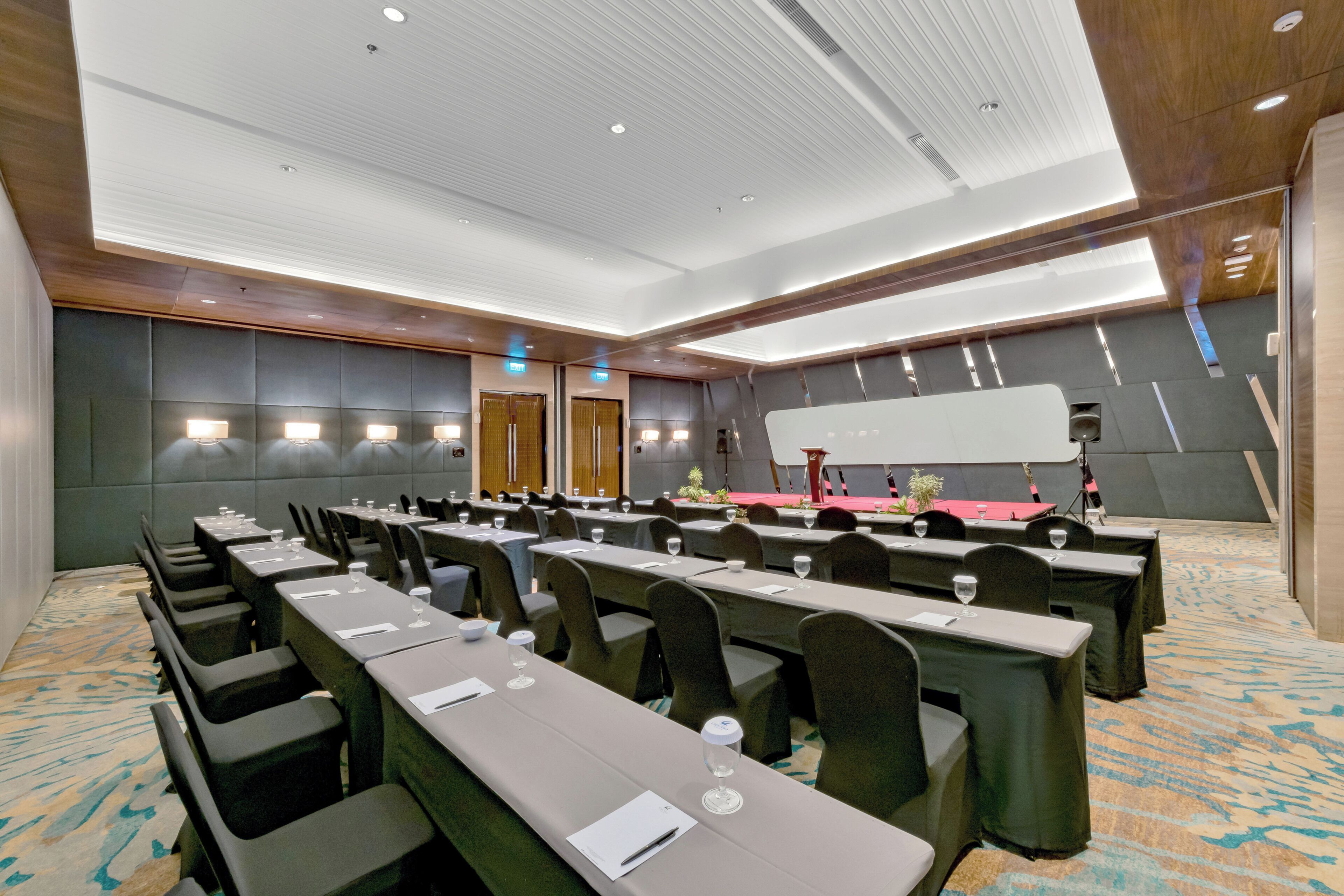 Uma sala de conferências com várias mesas, cadeiras e um palco com um púlpito.