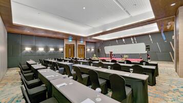 Uma sala de conferências com várias mesas, cadeiras e um palco com um púlpito.