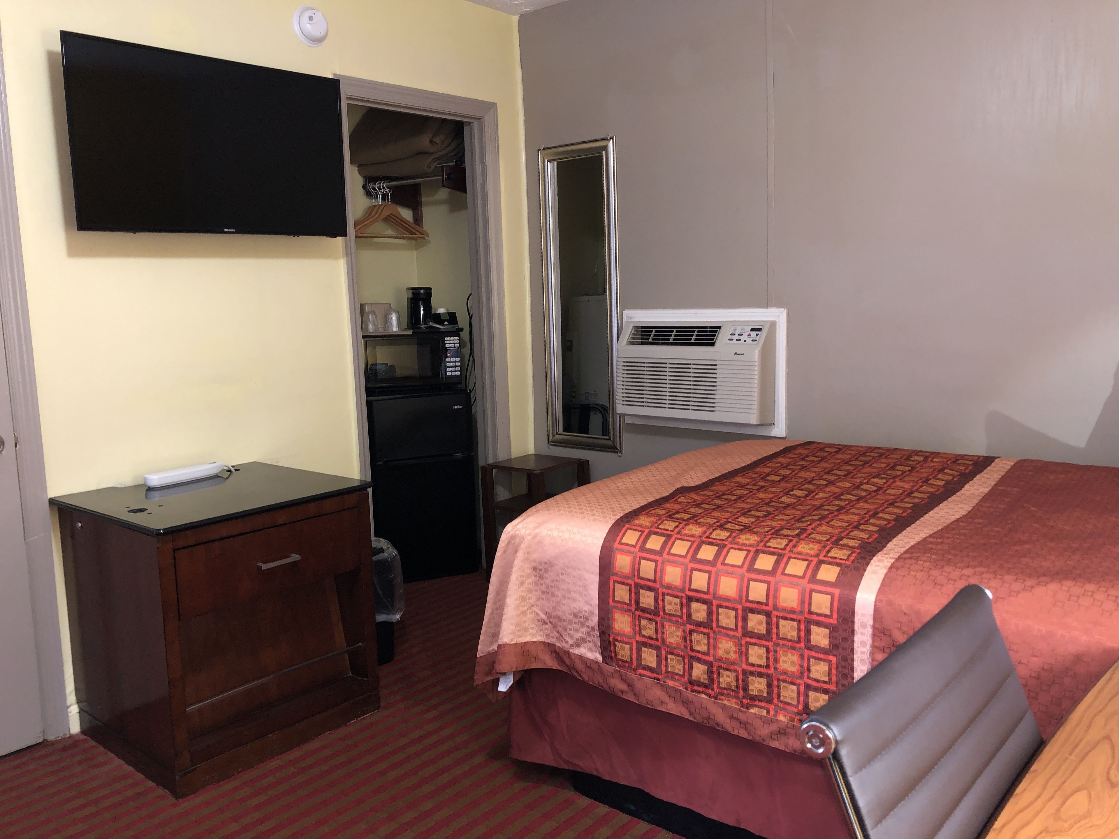 Une chambre d’hôtel équipée d’un lit, d’un bureau, d’une télévision, d’une armoire et d’un appareil de climatisation.