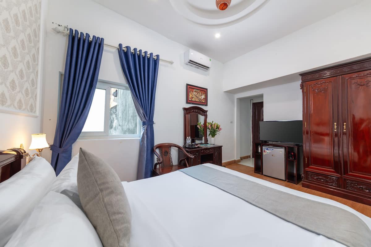 A hotel room with a bed, a desk, a TV, and a wardrobe.