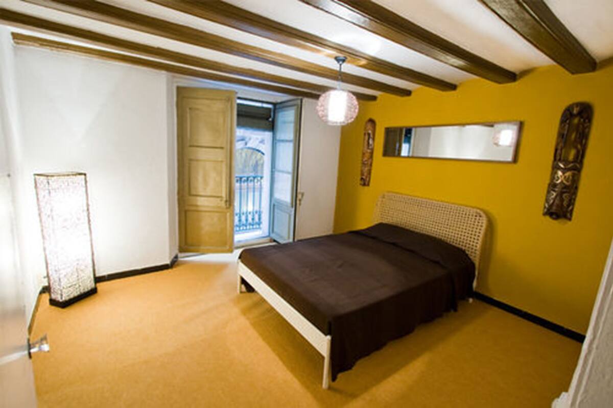 A bedroom with a bed, a door, a mirror, and a light fixture.