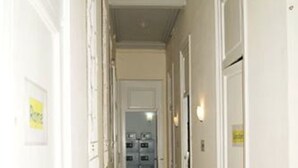 A hallway with a patterned carpet, white walls, and doors leading to rooms. - Palace Guesthouse (Barcelona)