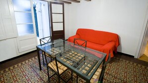 A room with a glass-top table, a red sofa, and patterned floor tiles. - Palace Guesthouse (Barcelona)
