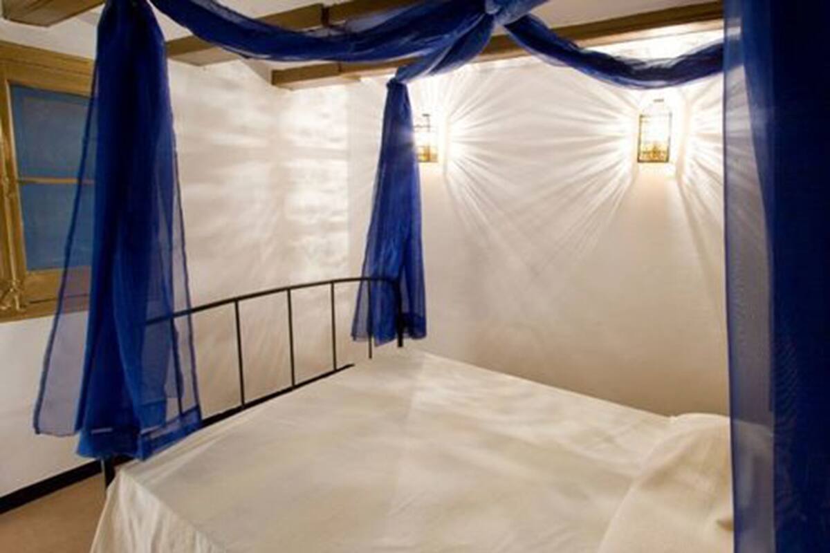 A room with a bed, a wooden headboard, and a white wall.