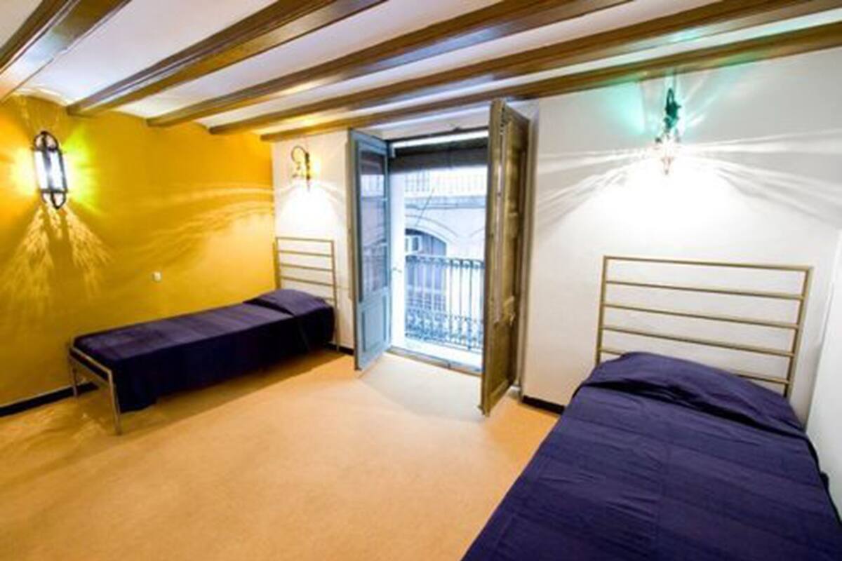 A room with two beds, a bench, and a balcony view.