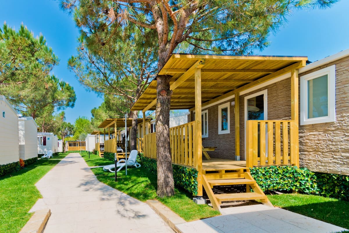 A row of mobile homes with wooden decks and a paved walkway.