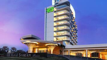 A modern hotel with a unique curved facade, multiple balconies, and a prominent 'HS' sign.