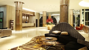 A spacious lobby with a reception desk, a black sofa, and a coffee table.