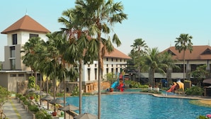 A swimming pool with slides, palm trees, and lounge chairs.