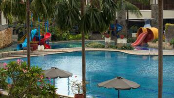 A swimming pool with slides and palm trees.