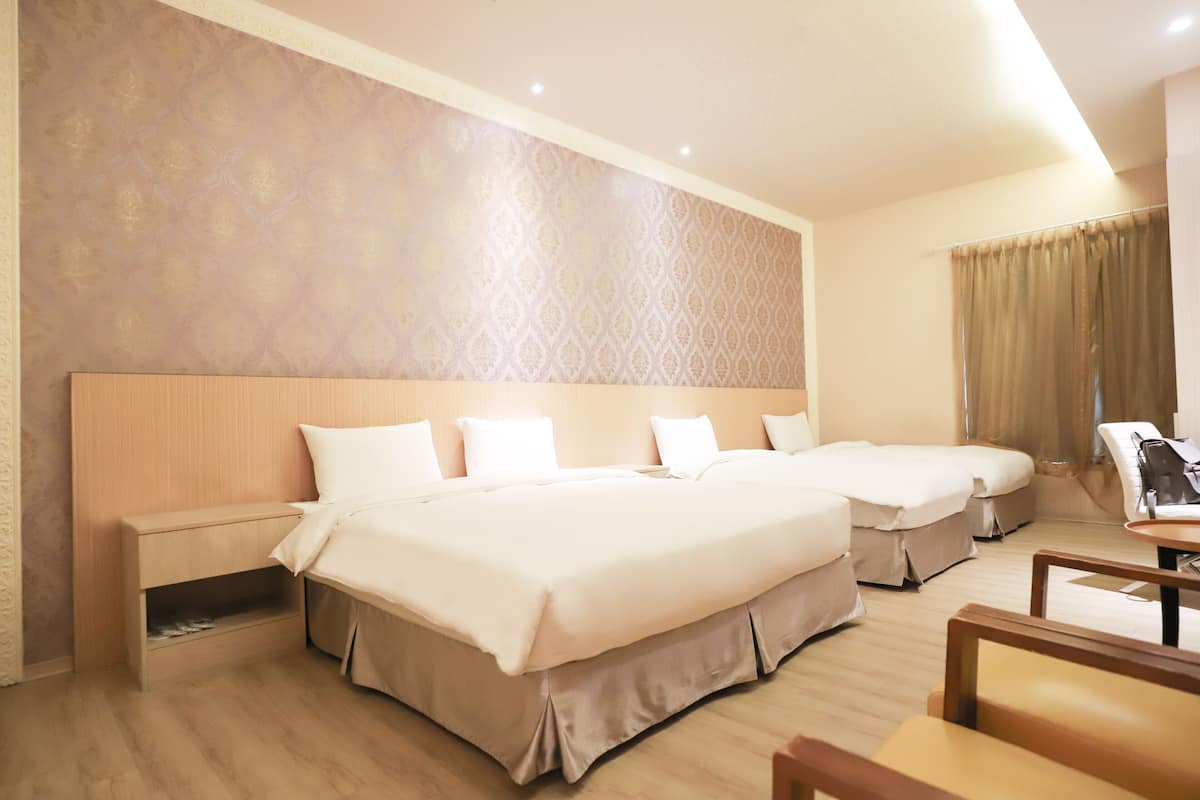A hotel room with two beds, a wooden headboard, a bedside table, and a chair.