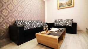 A living room with patterned wallpaper, a black and white sofa set, a wooden coffee table, and a framed painting on the wall. - Anho Chew Hotel (Luodong)