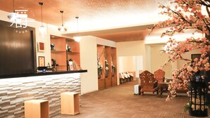 A hotel lobby with a reception desk, wooden chairs, a seating area, and a decorative plant. - Anho Chew Hotel (Luodong)