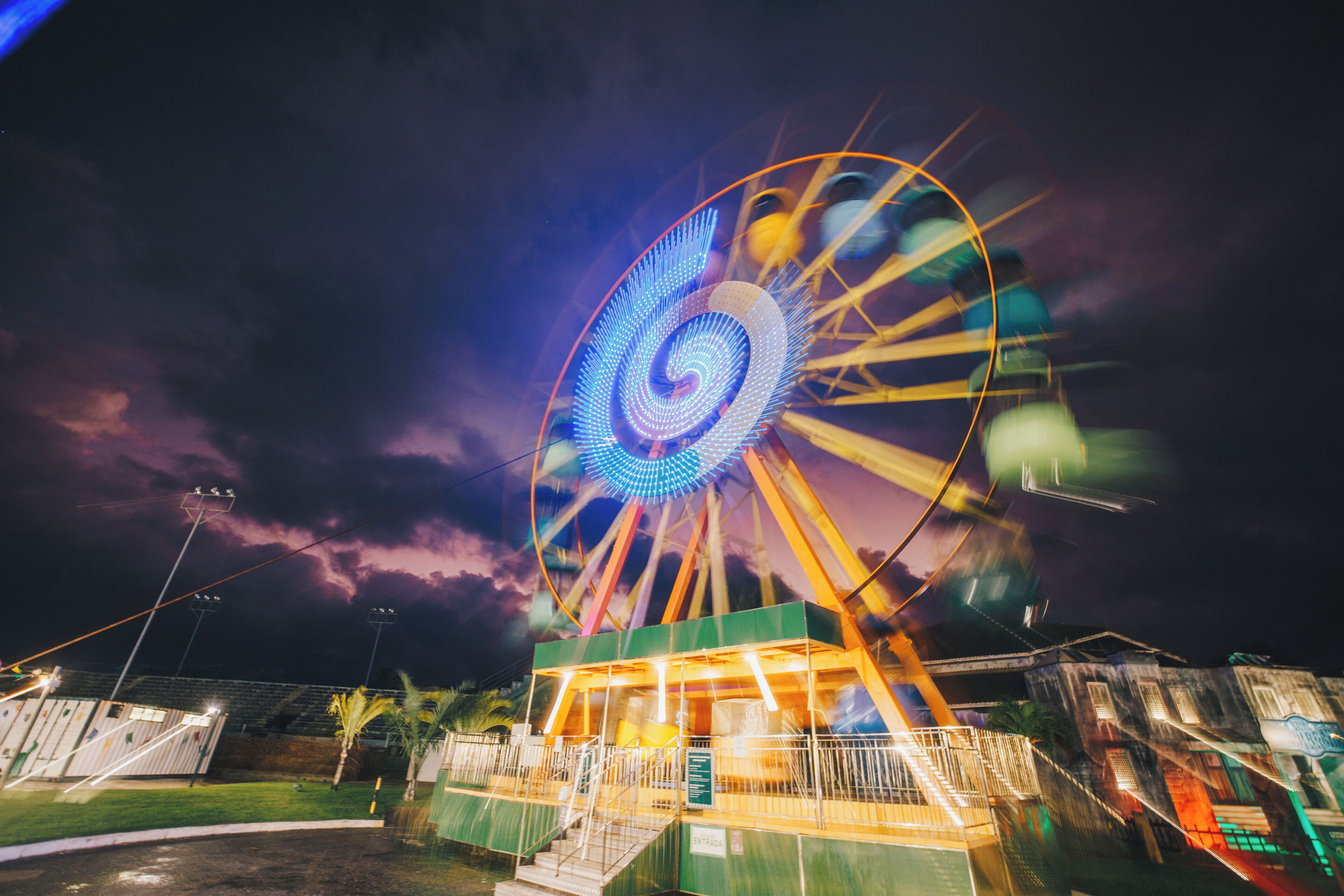 A Ferris wheel at night with a dark sky and a building in the foreground.