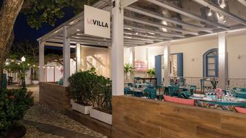 Un restaurant doté d’une terrasse, une enseigne indiquant « LA VILLA », et un chemin de pierres menant à l’entrée.