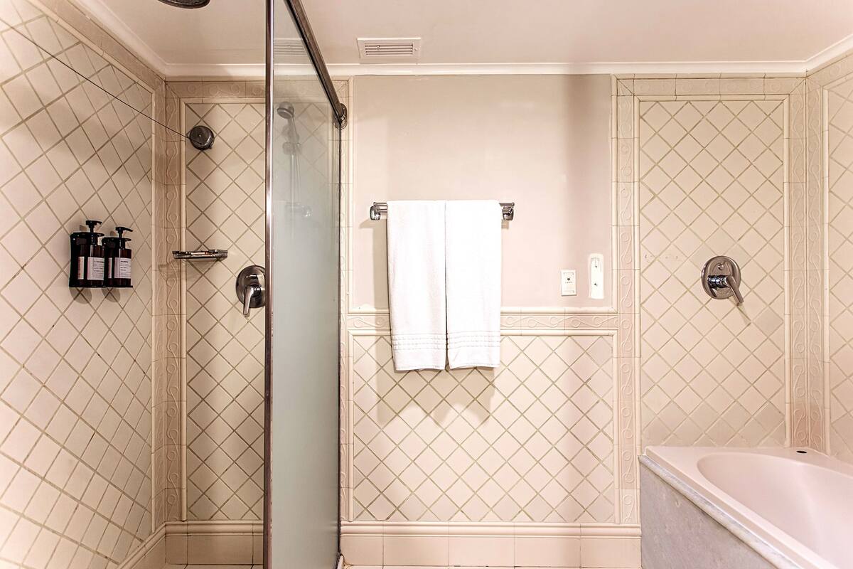A bathroom with a shower, a bathtub, and a glass-enclosed shower area.