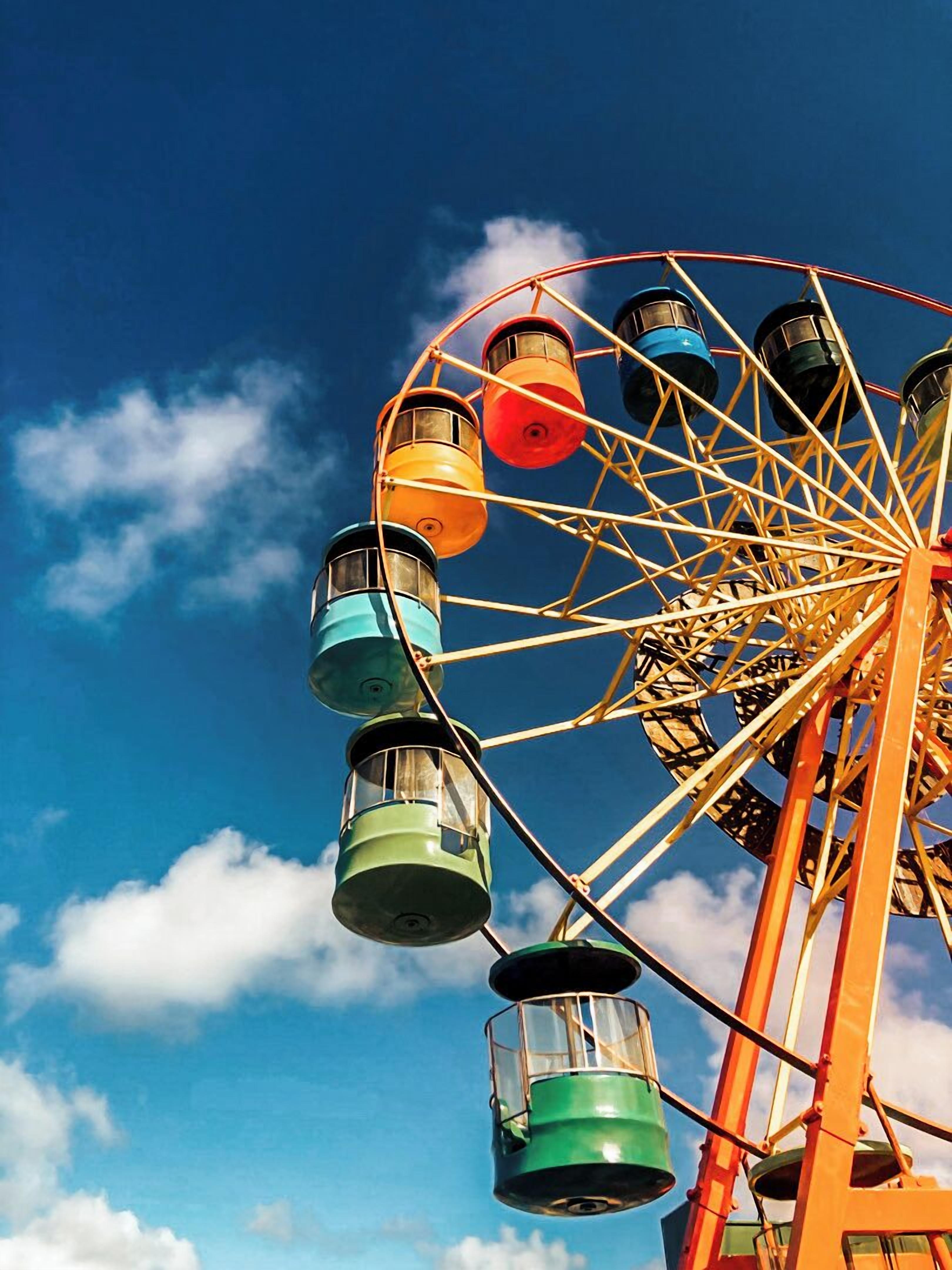 A Ferris wheel with colorful cabins against a blue sky.